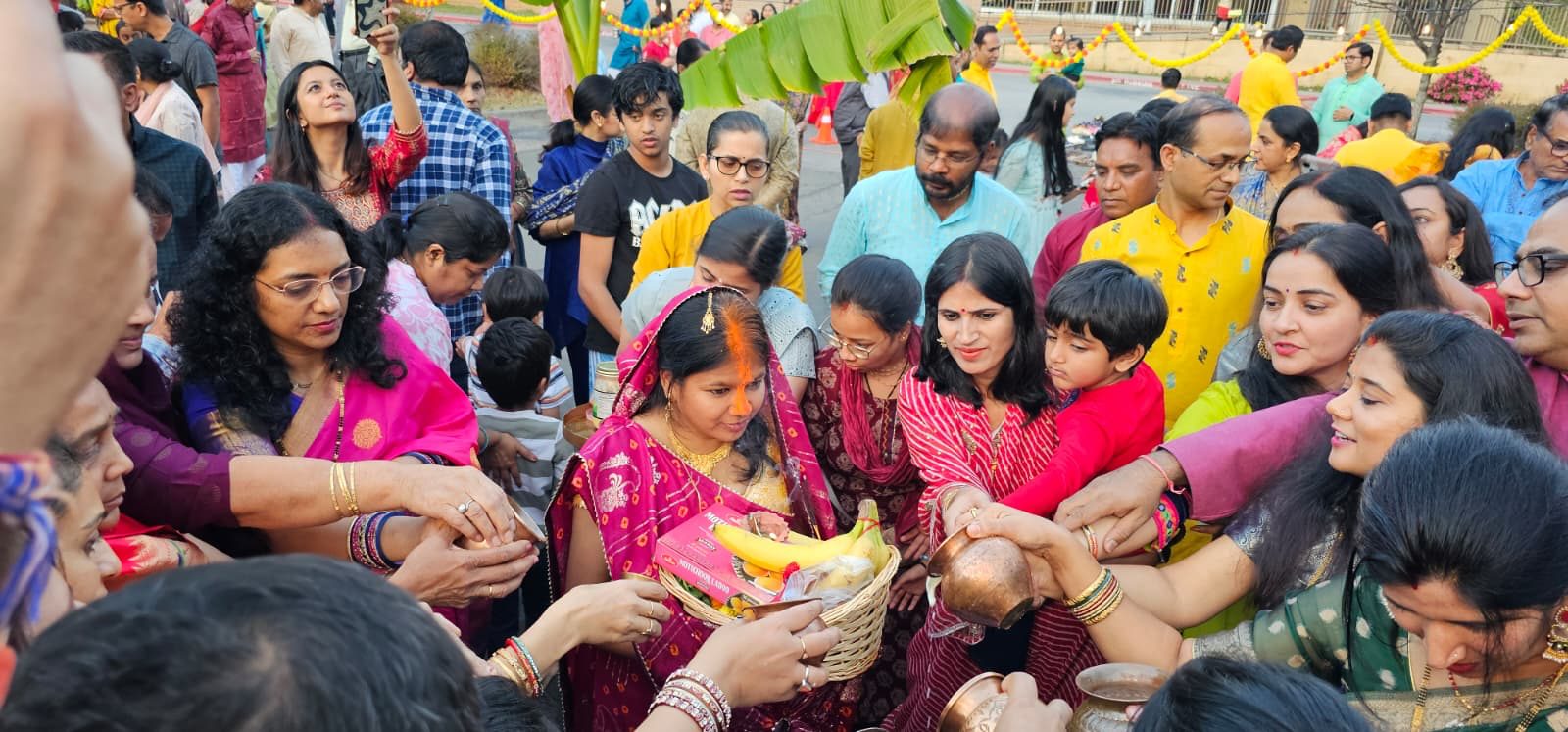 Families gathered close around a Vrati, pouring water from copper lotas over her offering basket
