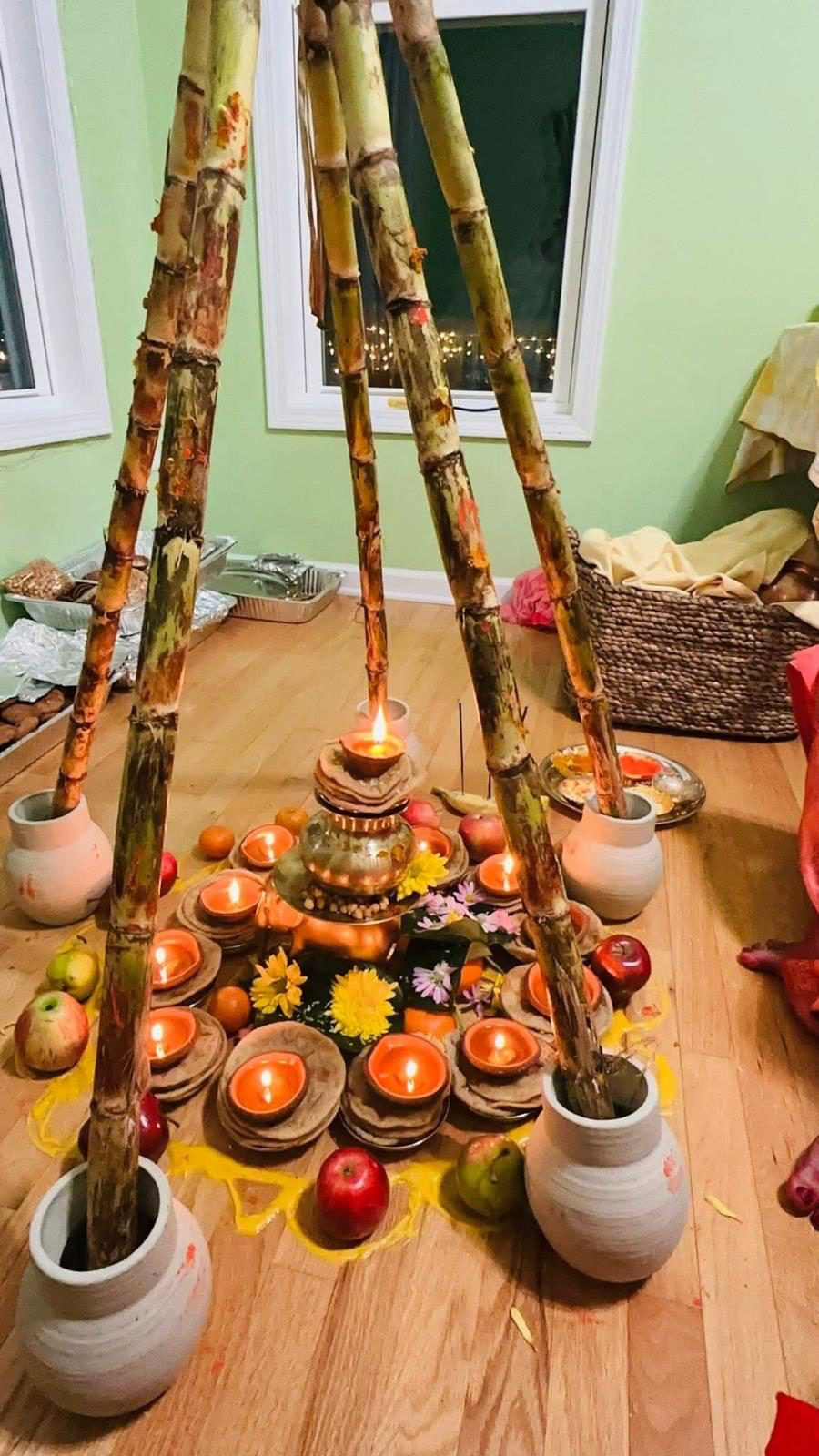 Sugarcane stalks tied above earthen pots, ringed by lit clay diyas, fruit and flowers for Kosi Bharai